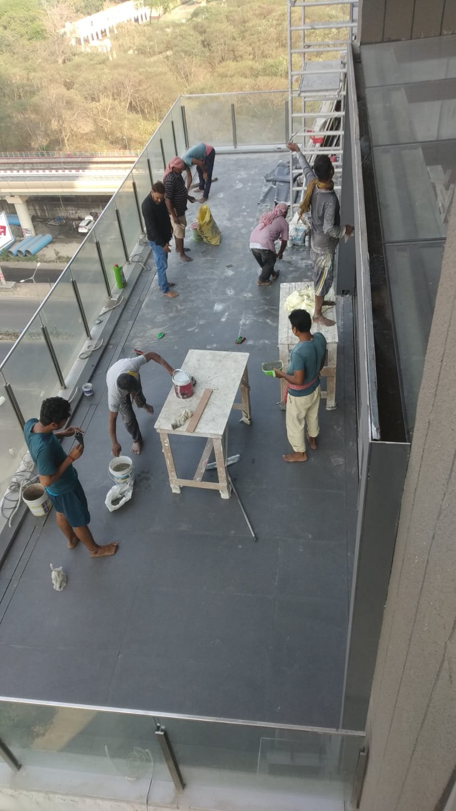 Before — bare terrace with workers on grey stone, Kolkata skyline