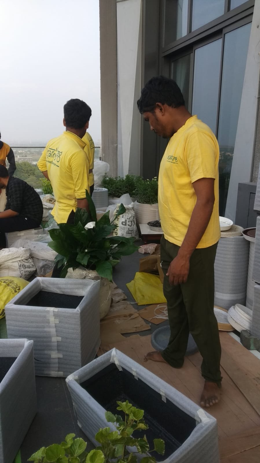 KarmYog team in yellow shirts assembling planters on the terrace